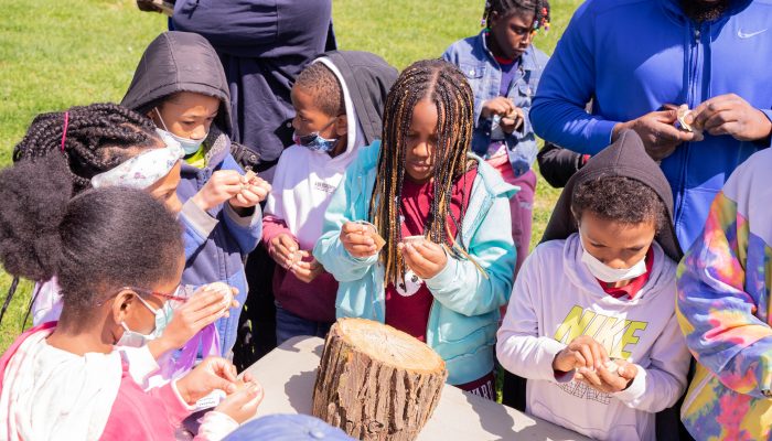 Students from Samuel Gompers Elementary School create tree cookie necklaces at Belmont Plateau