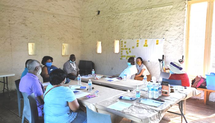 A group of eight people sit in a room around a table and participate in a co-design session.