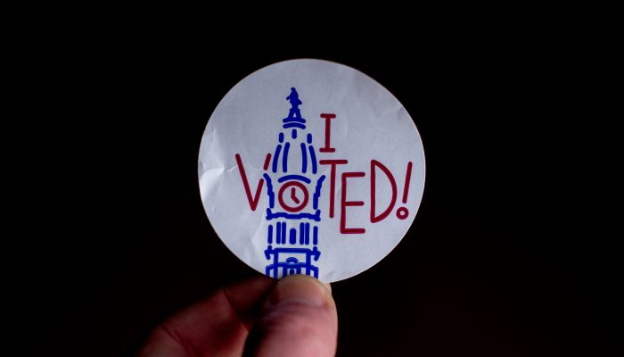 Hand holding a sticker that reads "I voted!"