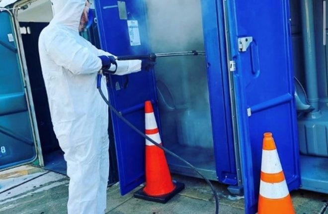 Jason Whittle, Public Restroom Specialist, power washing a porta-potty at Prevention Point