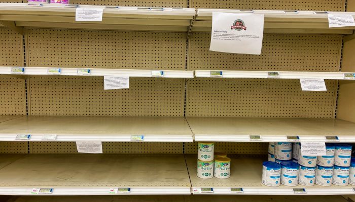 Nearly empty store shelves with only a few cans of infant formula on them