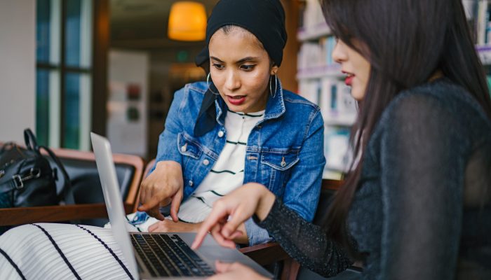 Two women pointing to information showing on a computer screen