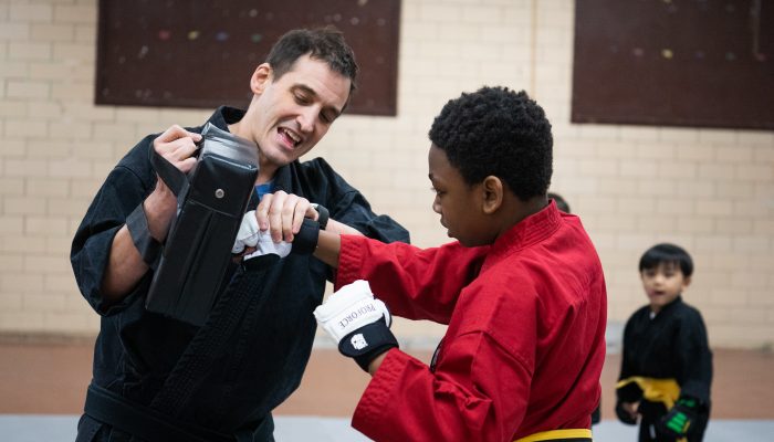 Karate teacher showing student how to punch a pad.