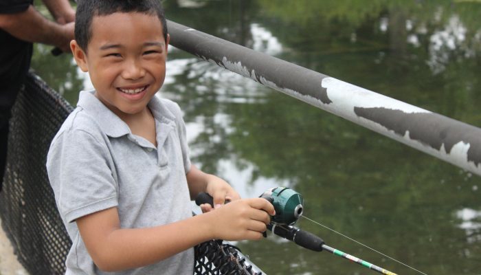 A boy fishing off the side of a bridge.