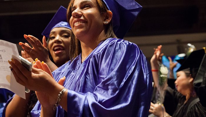 Two graduates applaud at a ceremony.