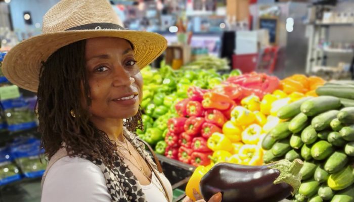 Trish Smith stands in front of a vegetable stand