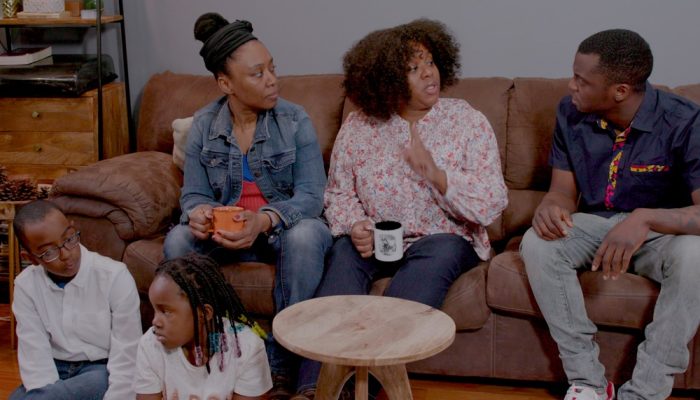 A family sits together on a couch and talks