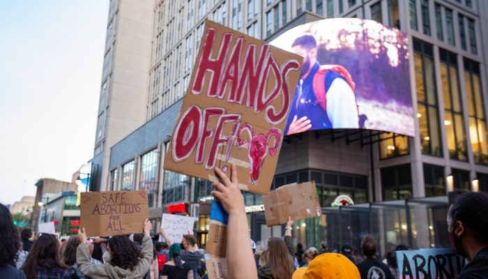 a person at a protest holding a sign that has a uterus on it and says hands off