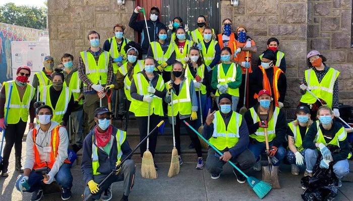 Um grande grupo de voluntários com vassouras e material de limpeza