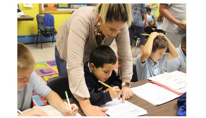A female recreation leader helps a child with his homework at recreation center.