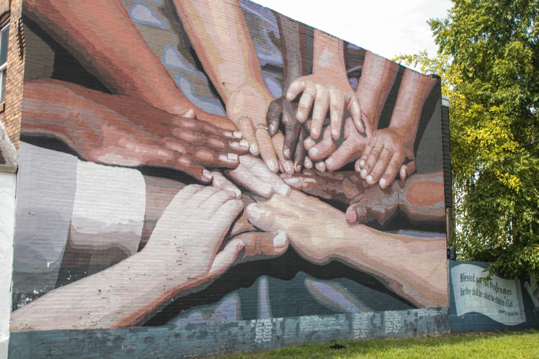 the mural "peace wall" which depicts many people of different races putting their hands together in the center