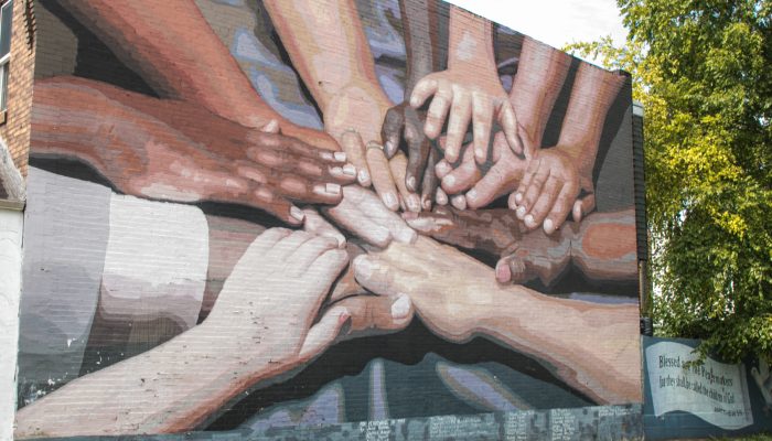 the mural "peace wall" which depicts many people of different races putting their hands together in the center