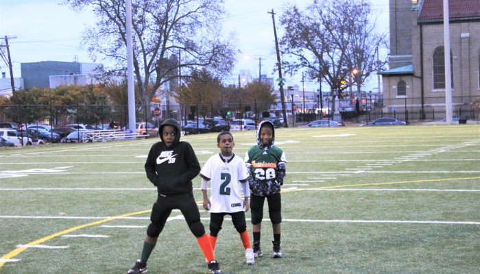 Three boys stand on a football field