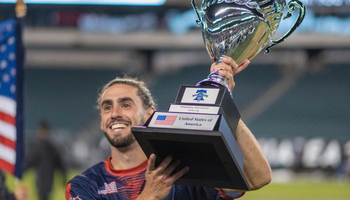 Golden boot winner Jason Rocha smiles and lifts the Unity Cup Trophy over his left shoulder after his Team USA defeated Team Liberia in the Championship match