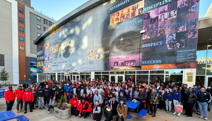 AmeriCorps members from various programs gather at the 2022 AmeriCorps Launch in front of a muraled building.