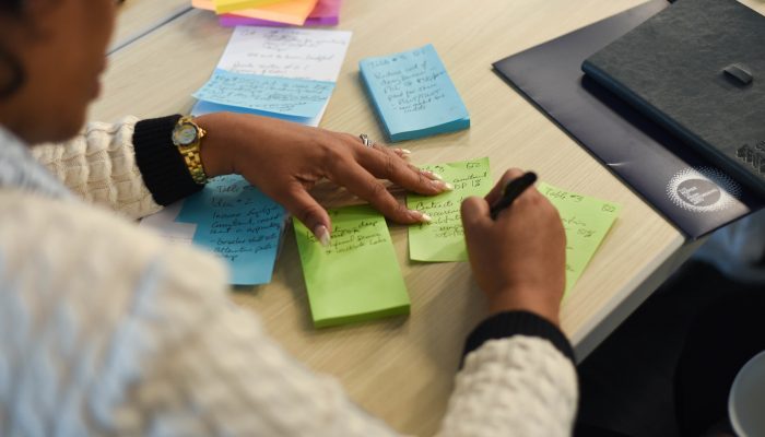 Picture of person writing on blue and green sticky notes