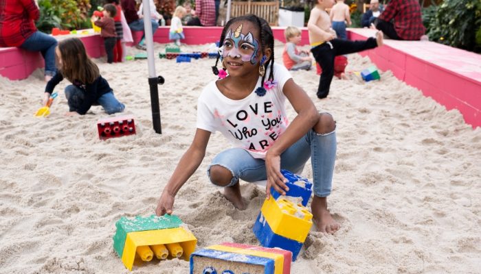African-American girl plays with blocks on the sand.