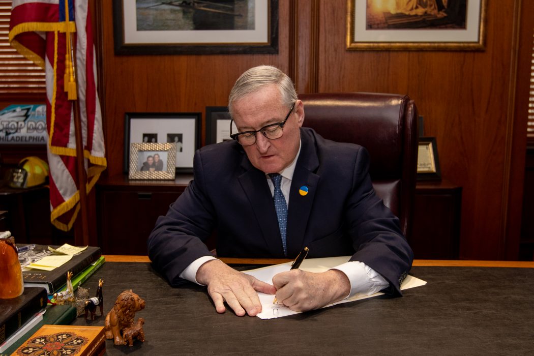 Mayor Jim Kenney signs the 17-111 executive order at his desk.
