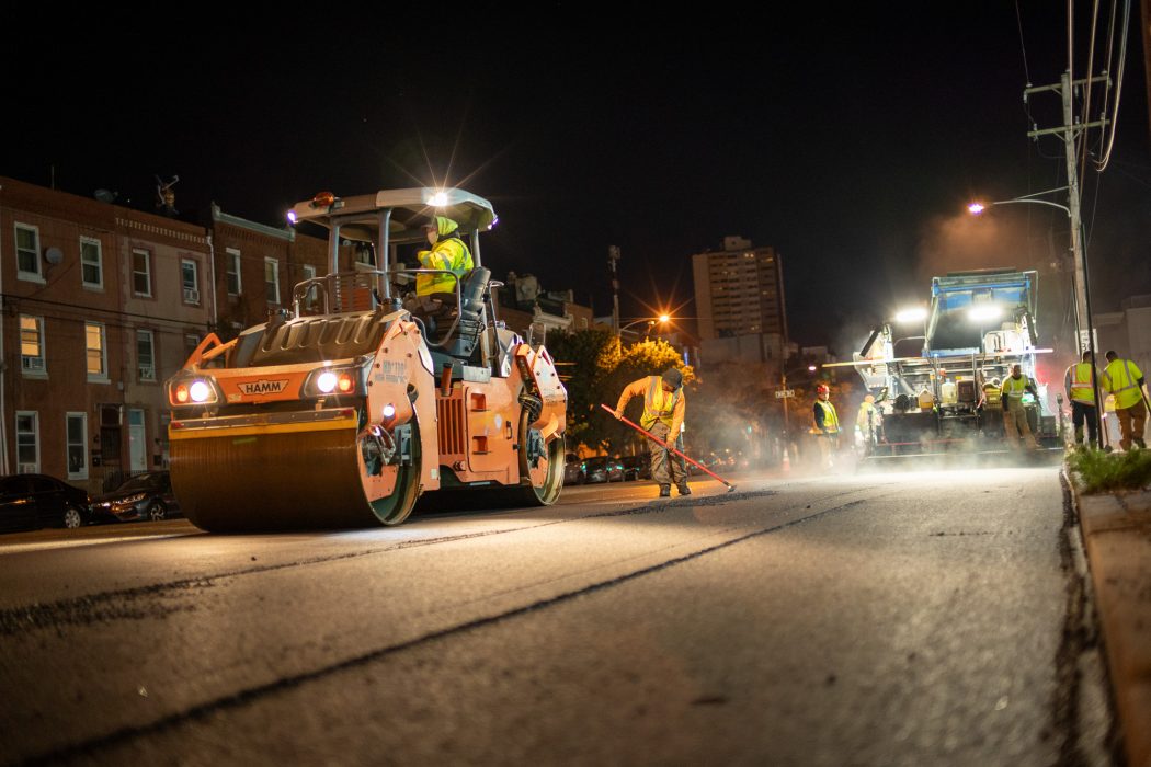a streets department crew paving a road at night