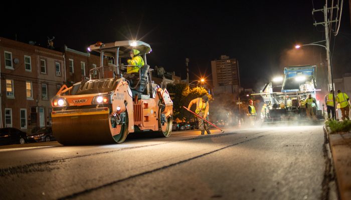 a streets department crew paving a road at night