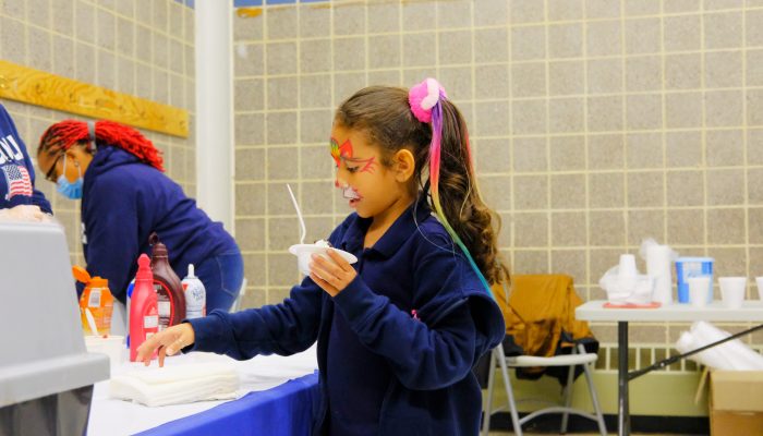 Child with face painting getting ice cream in a rec center