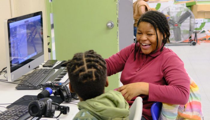 Two students sitting in a computer lab, smiling at one another