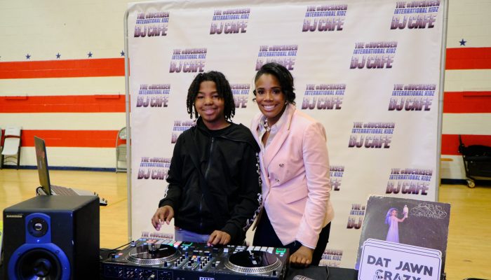 A woman smiles and shows a teenager how to use D.J. equipment.