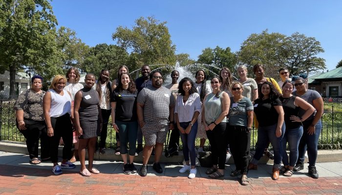 21 miembros del personal del MOCEVS se paran frente a la fuente de Franklin Square y sonríen para la foto.