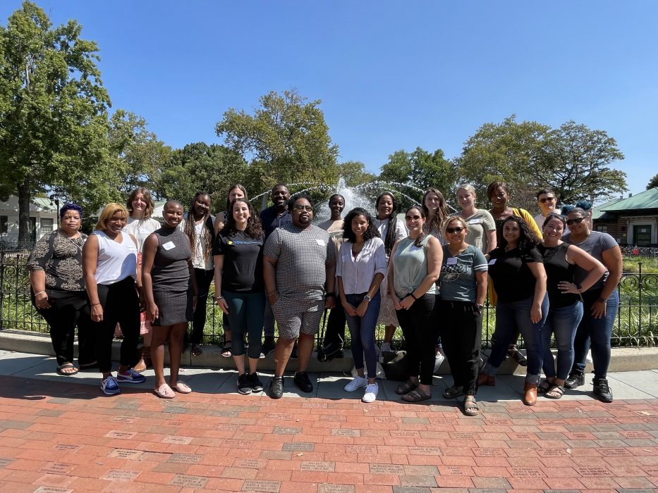 21 MOCEVS staff members stand in front of the Franklin Square fountain and smile for the photo.