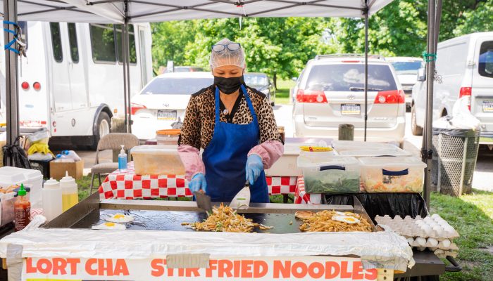 An asian woman tooks stir fried noodles at the Southeast Asian Market in FDR park.