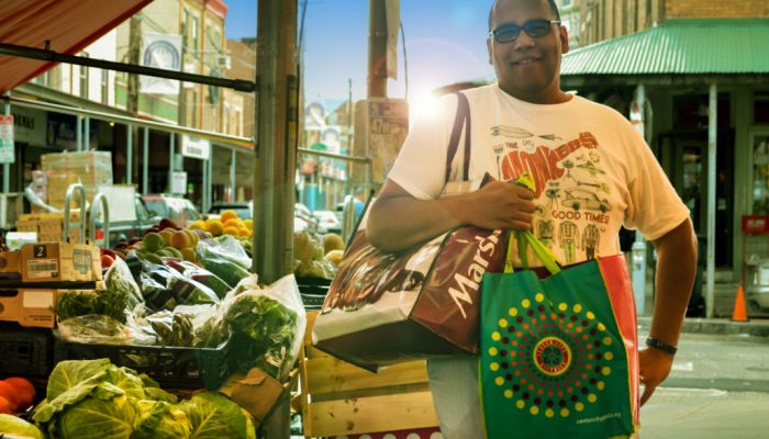 Person holding two reusable bags at market
