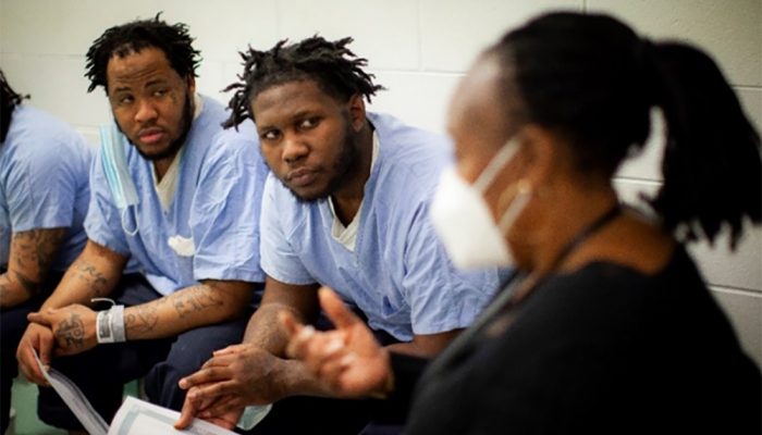 Two men listen intently to a social worker during the Fatherhood Program at Curran-Fromhold Correctional Facility.