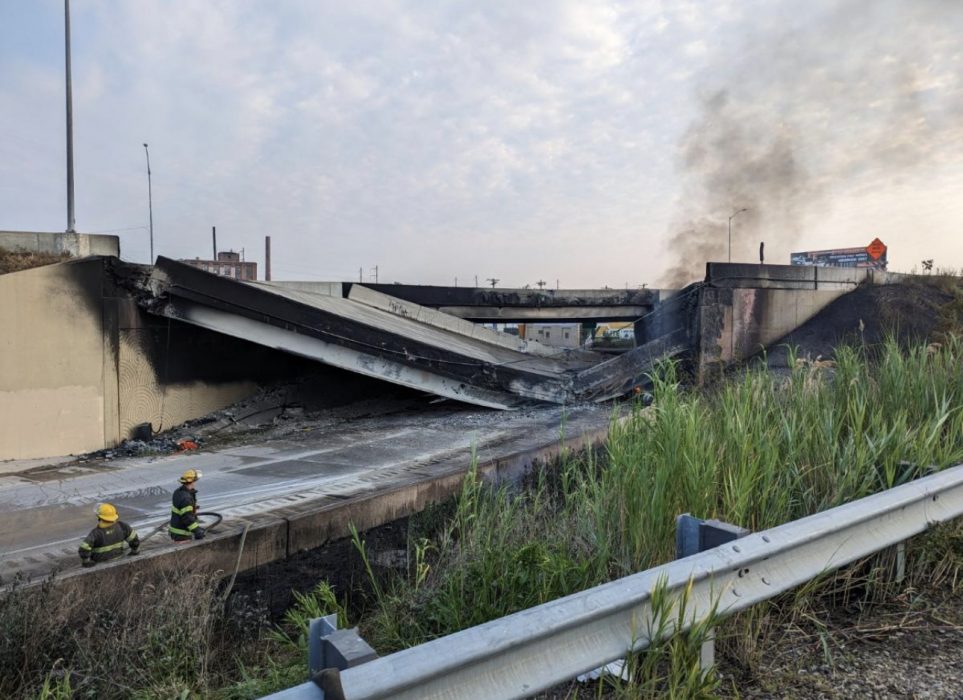 a section of I-95 that is collapsed with smoke coming out from under the rubble. Emergency personnel are in the bottom left hand corner