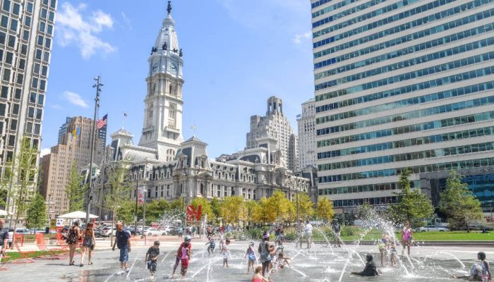 Children splash in fountains in LOVE Park on a hot day. Philadelphia City Hall stands tall in the background.