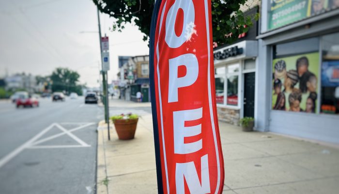 A red open sign on a sidewalk in front of a business