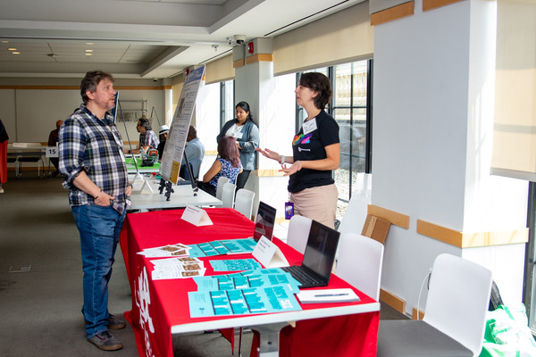 Guests interacting with project teams at their project display tables.