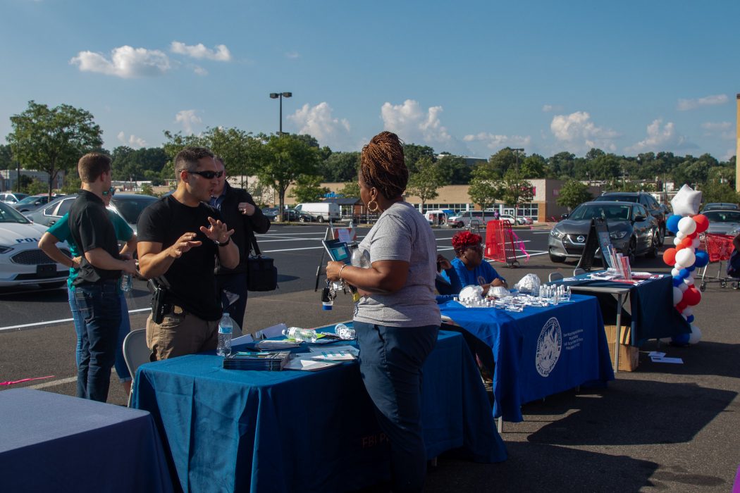 Picture shows a law enforcement officer speaking with a resident at an information table.