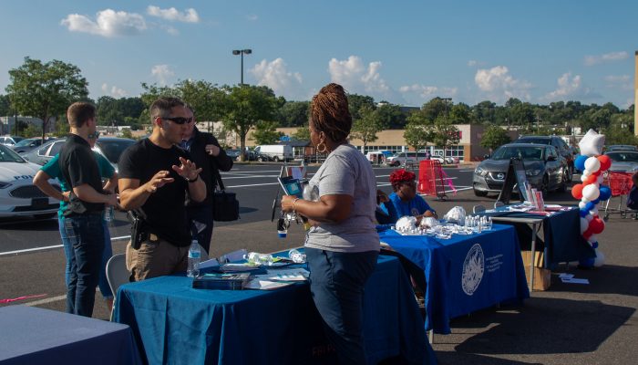 Picture shows a law enforcement officer speaking with a resident at an information table.