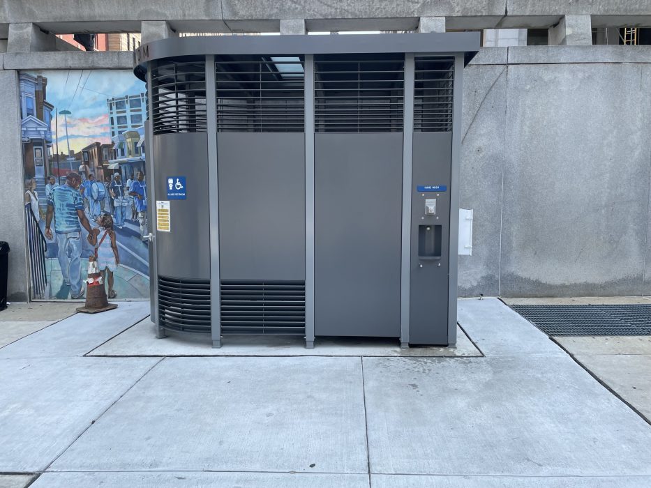 Public Restroom alongside the outside wall of the Municipal Services Building. There is a mural on the wall to the left of the public restroom.