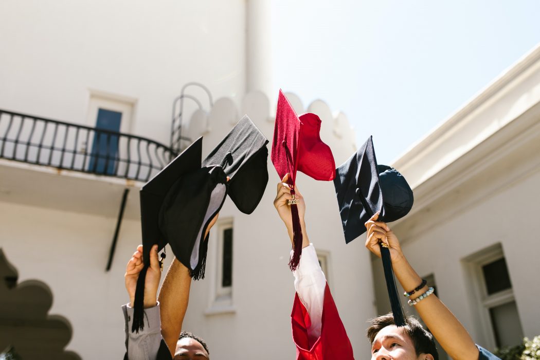 Graduates toss their caps into the air