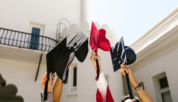 Graduates toss their caps into the air