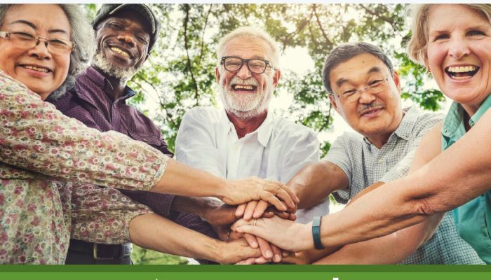 A group of diverse older adults smiling at the camera outside.