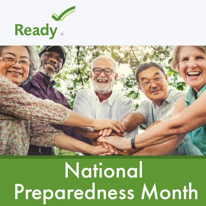 A group of diverse older adults smiling at the camera outside.