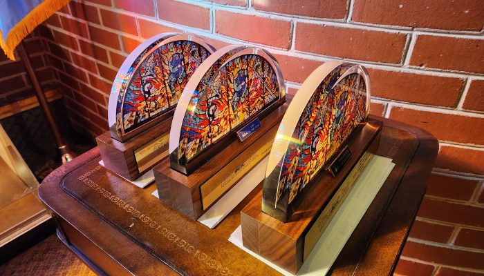 table with three awards shaped liked semi-circular stained glass windows