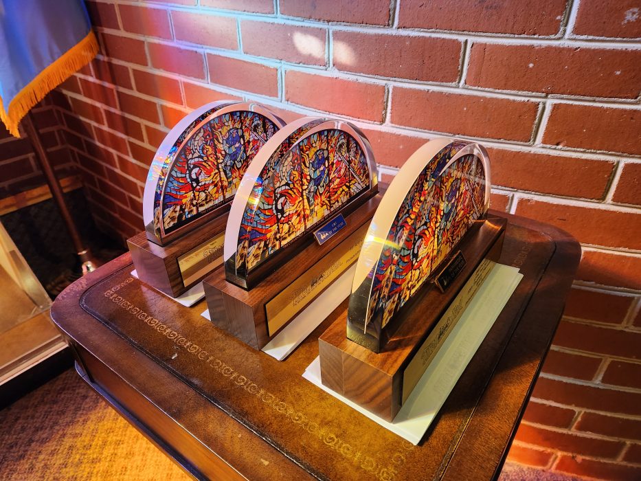 table with three awards shaped liked semi-circular stained glass windows