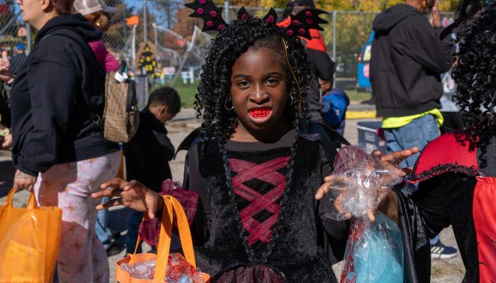 An African-American girl is dressed up as Dracula at a Parks & Rec Halloween party outside.