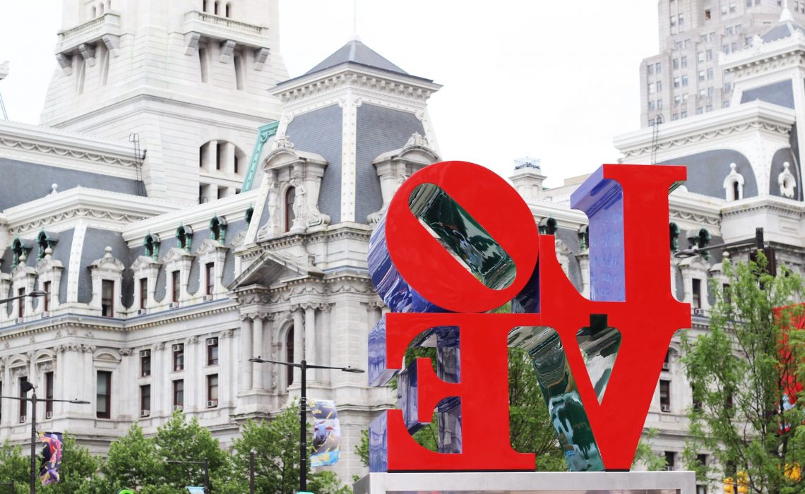 the love sculpture in the foreground with Philadelphia City Hall in the background