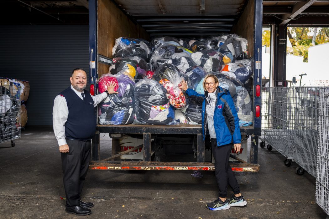 Race Director Kathleen Titus and Major Daniel Alverio stand in front of a truck that is filled with hundreds of bags of discarded clothing items from Philadelphia Marathon Weekend.