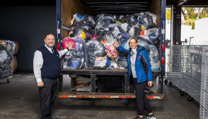 Race Director Kathleen Titus and Major Daniel Alverio stand in front of a truck that is filled with hundreds of bags of discarded clothing items from Philadelphia Marathon Weekend.