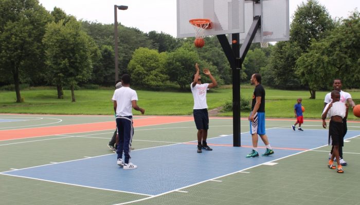 Youth play basketball on newly renovated basketball courts at Eastwick Park.